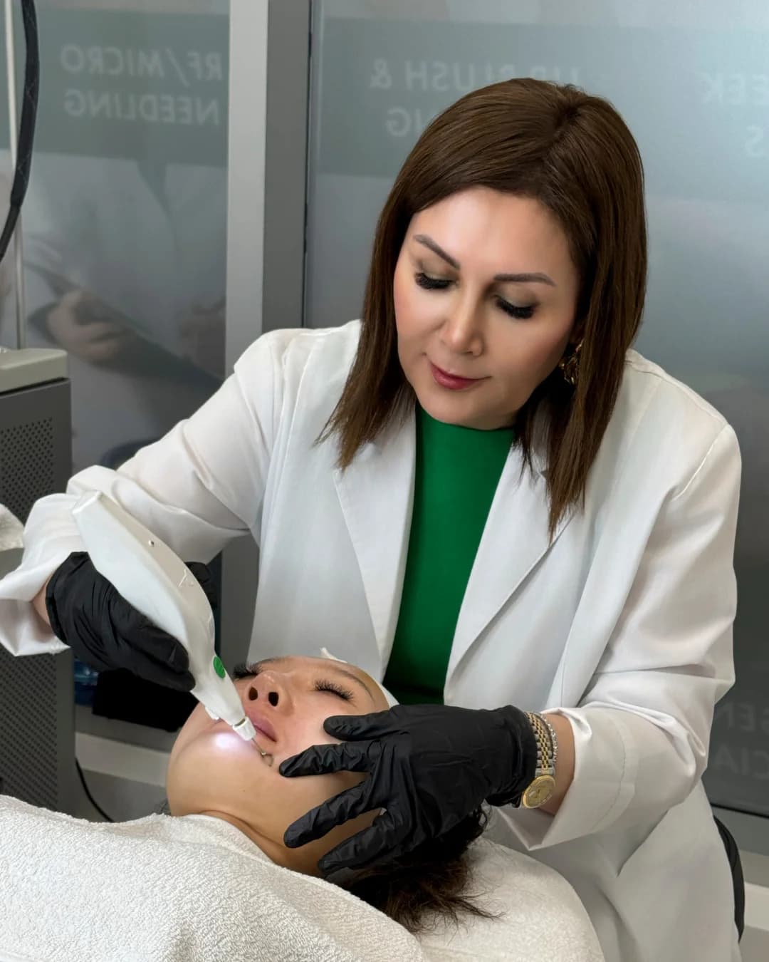 Clinician in gloves applying a handheld device to a reclining patient’s face